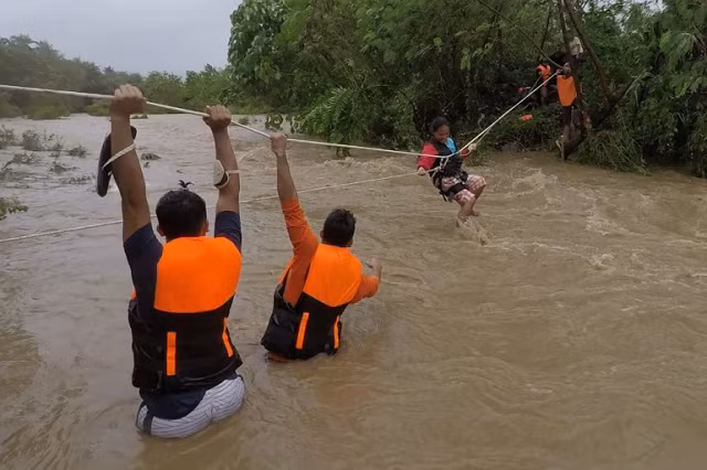 Nhân viên cứu hộ sơ tán người dân ở gần một con sông tràn bờ.