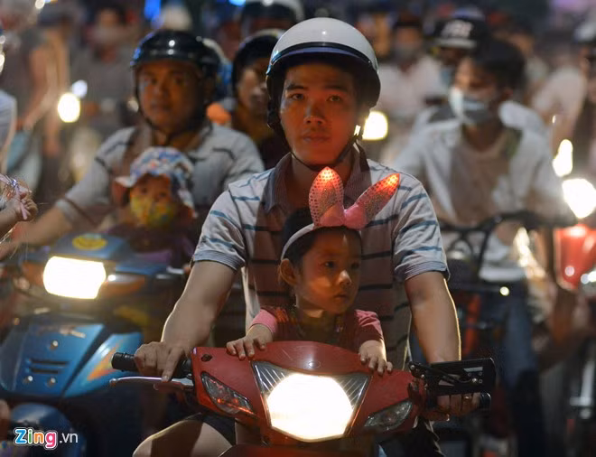 Các em nhỏ được bố mẹ chở xe máy đi chơi. Hàng chục nghìn người phá cỗ trông trăng
