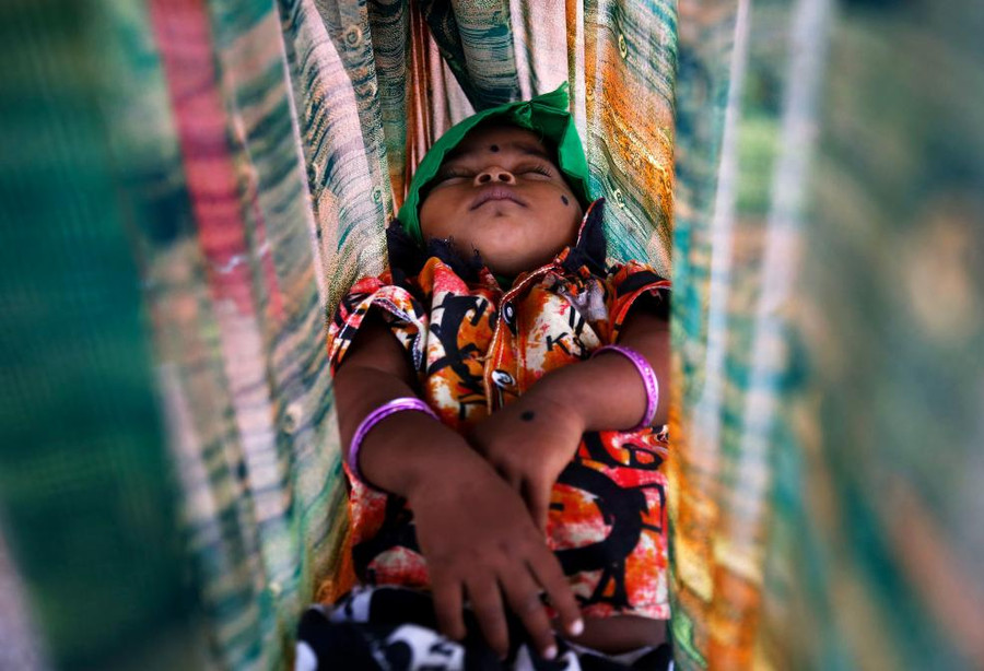 Một em bé đang ngủ ngon trên võng bên ngoài một công trình xây dựng ở Bengaluru, Ấn Độ.