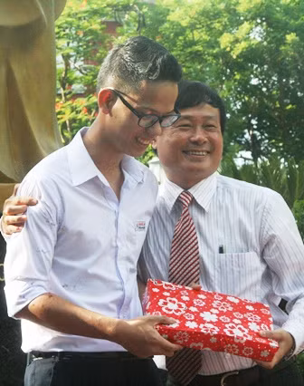 Em Đoàn Quốc Hoài Nam - Học sinh đoạt Huy chương Bạc Olympic Hóa học Quốc tế, tặng sách, vở ghi môn Hóa học cho thầy Nguyễn Phước Bửu Tuấn.