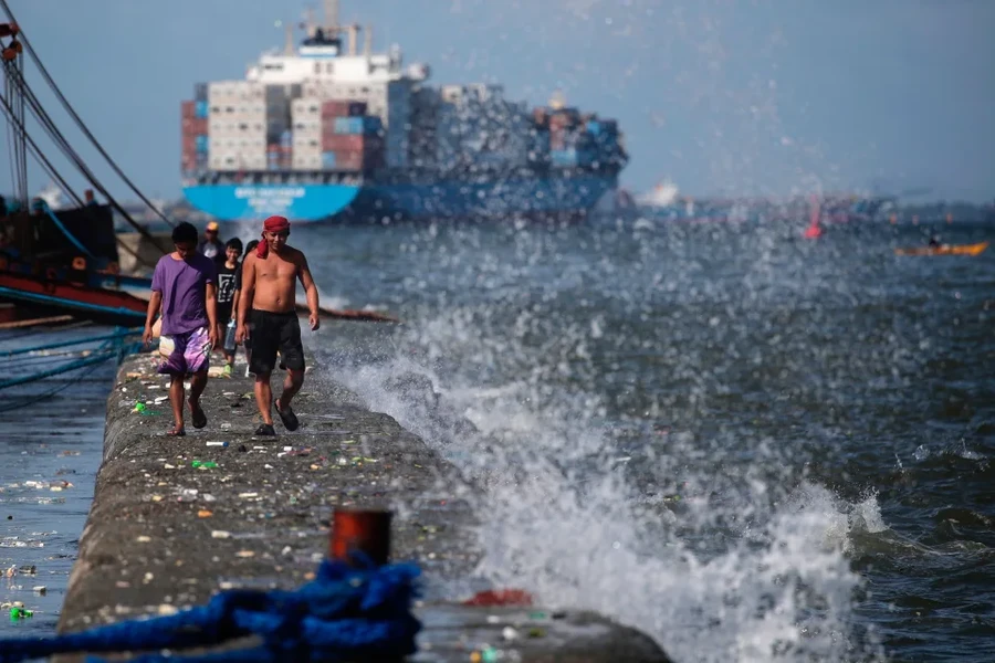 Ngư dân Philippines di chuyển trên một con đê chắn sóng ở Manila khi bão Mawar đang tới gần. (Ảnh: EPA).