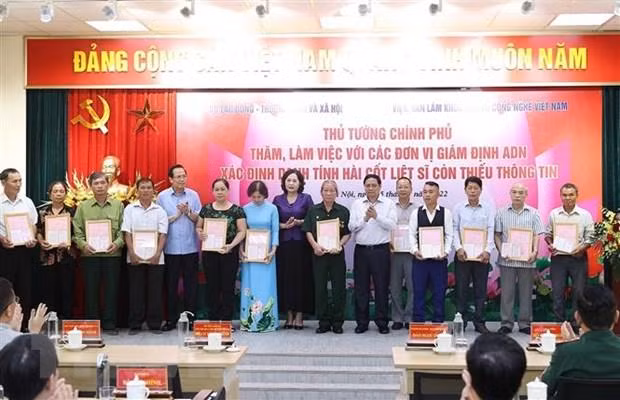 Thủ tướng Phạm Minh Chính trao kết quả giám định ADN cho gia đình liệt sỹ. (Ảnh: Dương Giang/TTXVN).