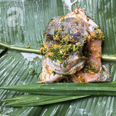 Nhồi lá nếp vào bên trong, gập đôi cá và dùng que tre kẹp vào giữa con cá đã gập đôi, buộc chặt 2 đầu que tre.