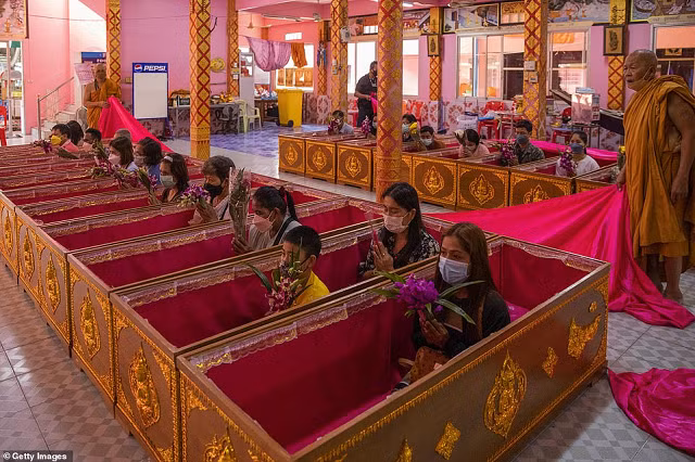 Những tín đồ Thái Lan nằm trong quan tài trong một buổi lễ hồi sinh để tẩy sạch nghiệp xấu vào cuối năm.
