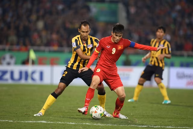 Cầu thủ Việt Nam và Malaysia tranh bóng trên sân