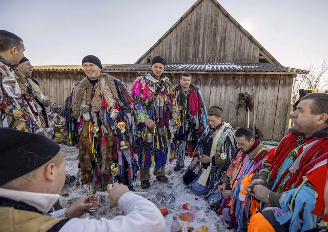 Dân làng mặc trang phục truyền thống nghỉ ngơi, ăn uống trong lễ hội Malanka. Ảnh: AP
