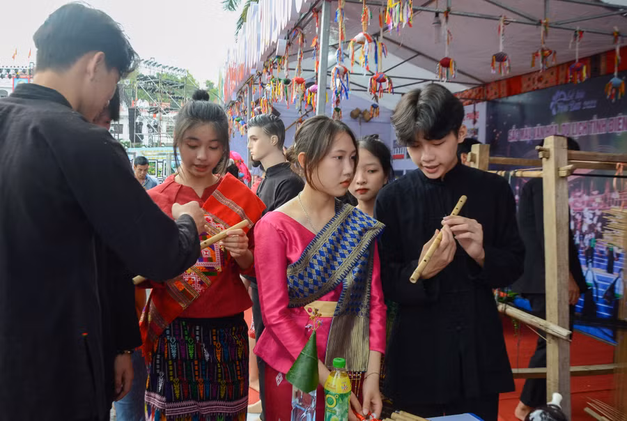 Các thanh niên trong trang phục truyền thống tìm hiểu về cây sáo trúc của Việt Nam.
