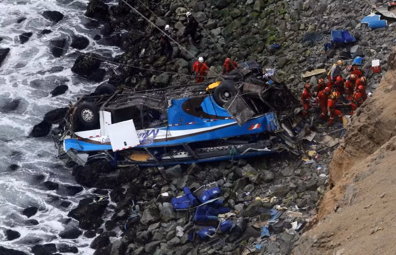 Nhân viên cứu hộ làm việc tại hiện trường khi một chiếc xe buýt va chạm với xe tải và lao xuống một mỏm đá ở Lima, Peru