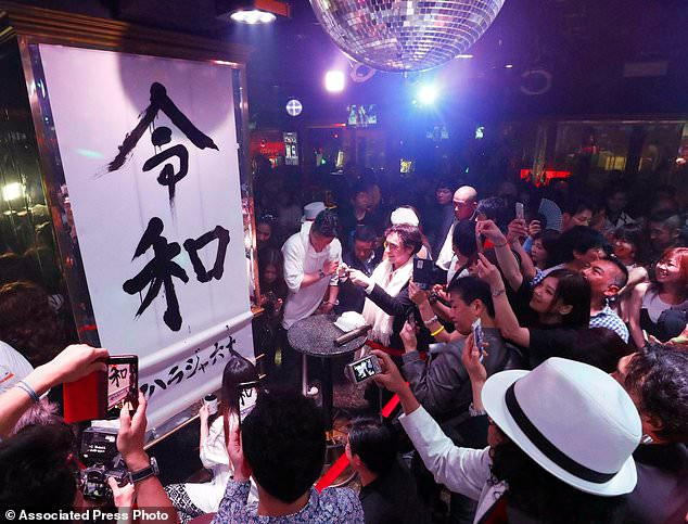 Người dân chúc mừng trước bức hình có tên triều đại Reiwa.