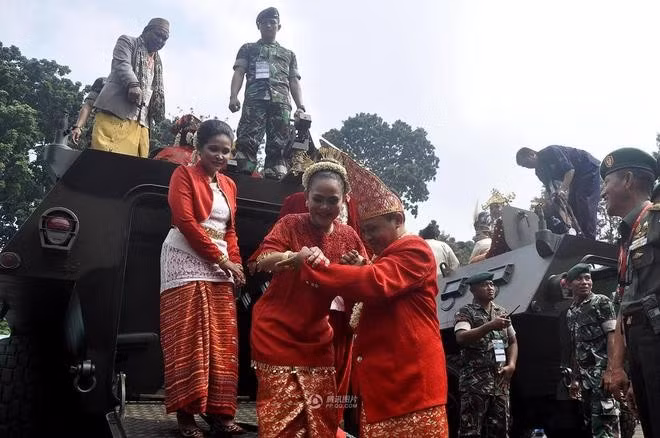 Chú rể đỡ bạn đời xuống xe bọc thép sau khi màn rước dâu kết thúc.