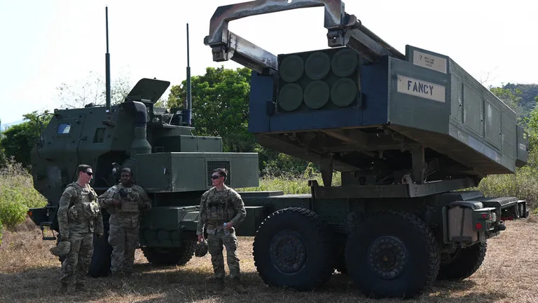 Binh sĩ quân đội Mỹ đứng cạnh bệ phóng hệ thống tên lửa pháo binh cơ động cao (HIMARS). (Ảnh: AFP)