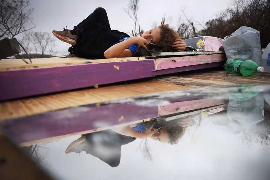 Một cô bé nằm nghỉ trên đống đổ nát ngôi nhà của mình sau bão Maria ở Puerto Rico Một cô bé nằm nghỉ trên đống đổ nát ngôi nhà của mình sau bão Maria ở Puerto Rico