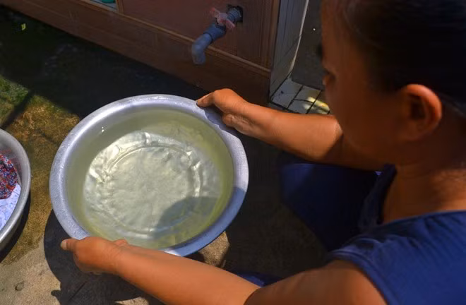 Nước giếng khoan làng Bái Thủy vừa bơm lên liền bốc mùi tanh, nổi váng và ngả màu vàng. Ảnh: Nguyễn Dương.