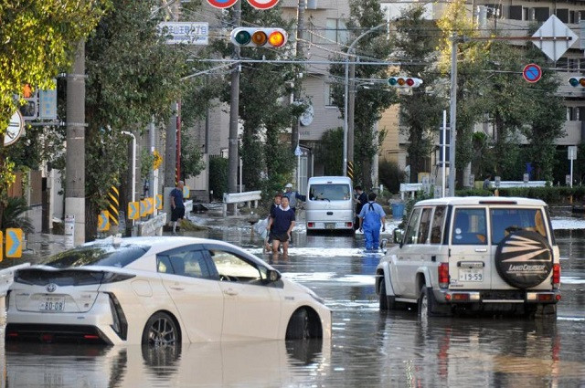 Mọi người đi bộ trong một con đường ngập nước ở Kawasaki, gần Tokyo Mọi người đi bộ trong một con đường ngập nước ở Kawasaki, gần Tokyo