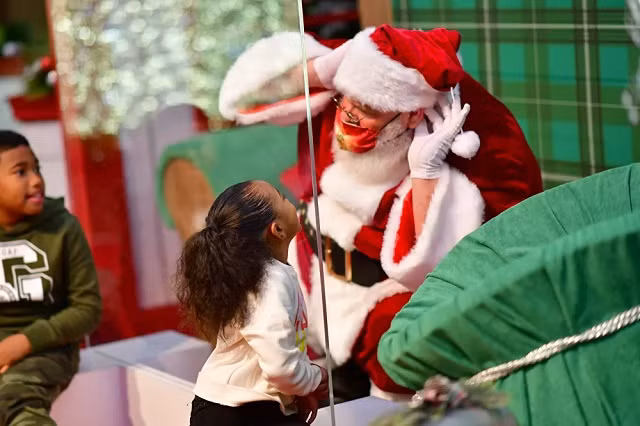 Trẻ em nói chuyện với ông già Noel, người ngồi sau dải phân cách bằng kính do đại dịch coronavirus (COVID-19)