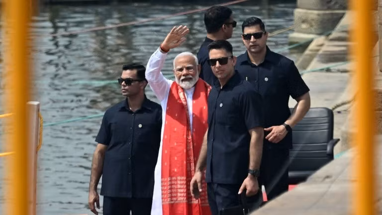Thủ tướng Ấn Độ Narendra Modi (giữa) vẫy tay sau khi cầu nguyện bên bờ sông Hằng ở Varanasi ngày 14/5. (Ảnh: AFP)