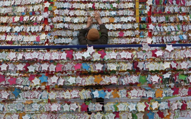 Một phụ nữ treo những mẩu giấy mang lời ước nguyện năm mới bên ngoài ngôi chùa Jogyesa ở Seoul, Hàn Quốc Một phụ nữ treo những mẩu giấy mang lời ước nguyện năm mới bên ngoài ngôi chùa Jogyesa ở Seoul, Hàn Quốc