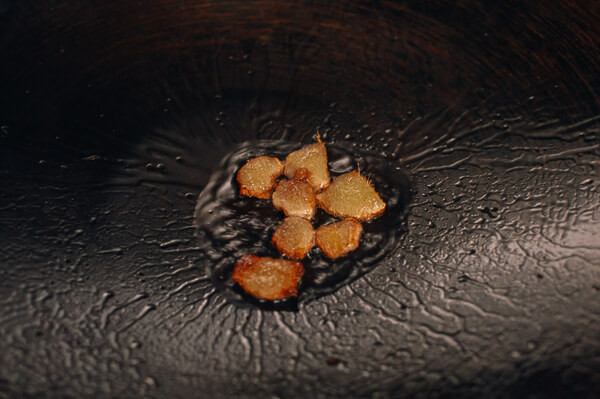 Bước 2: Trong thời gian đun hỗn hợp trên, làm sạch thịt gà. Trừ phần lườn gà không dùng đến, chặt phần thành những miếng to vừa. Cho dầu ăn vào chảo đặt trên lửa vừa phi gừng khoảng 1-2 phút.