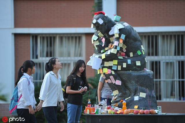 HS viết lời cầu nguyện lên mẩu giấy dán lên bức tượng The Thinker