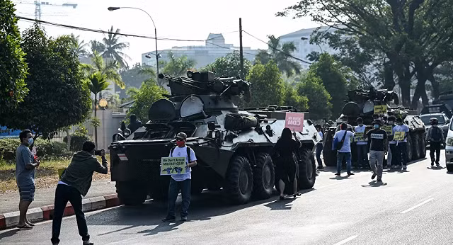 Người biểu tình có mặt bên cạnh các phương tiện của quân đội Myanmar.