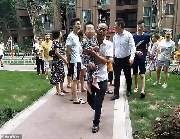 Một người hàng xóm bế cậu bé vừa thoát chết