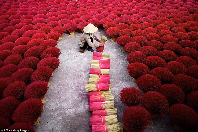 Một người phụ nữ Việt Nam đang gom nhang trong sân tại làng Quảng Phú Cầu ở ngoại ô Hà Nội