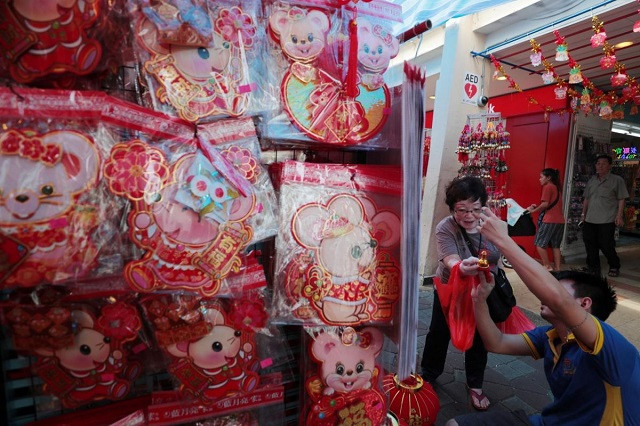 Người bán hàng giúp khách mua sắm tại gian hàng đồ trang trí năm mới của Trung Quốc ở Chong Pang, Singapore Người bán hàng giúp khách mua sắm tại gian hàng đồ trang trí năm mới của Trung Quốc ở Chong Pang, Singapore