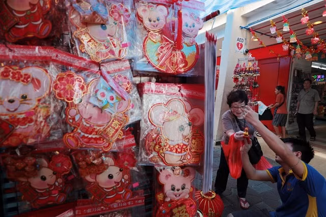 Người bán hàng giúp khách mua sắm tại gian hàng đồ trang trí năm mới của Trung Quốc ở Chong Pang, Singapore Người bán hàng giúp khách mua sắm tại gian hàng đồ trang trí năm mới của Trung Quốc ở Chong Pang, Singapore