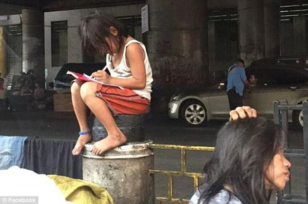 Xúc động ảnh bé gái mải mê làm bài tập trên bục chắn đường