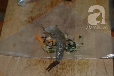 Bánh tráng (bánh đa nem) gấp đôi theo đường chéo để tạo hình tam giác, múc 1 muỗng nhân lên rồi đặt con tôm vào chính giữa, phần đuôi tôm hướng ra ngoài rồi gói lại.