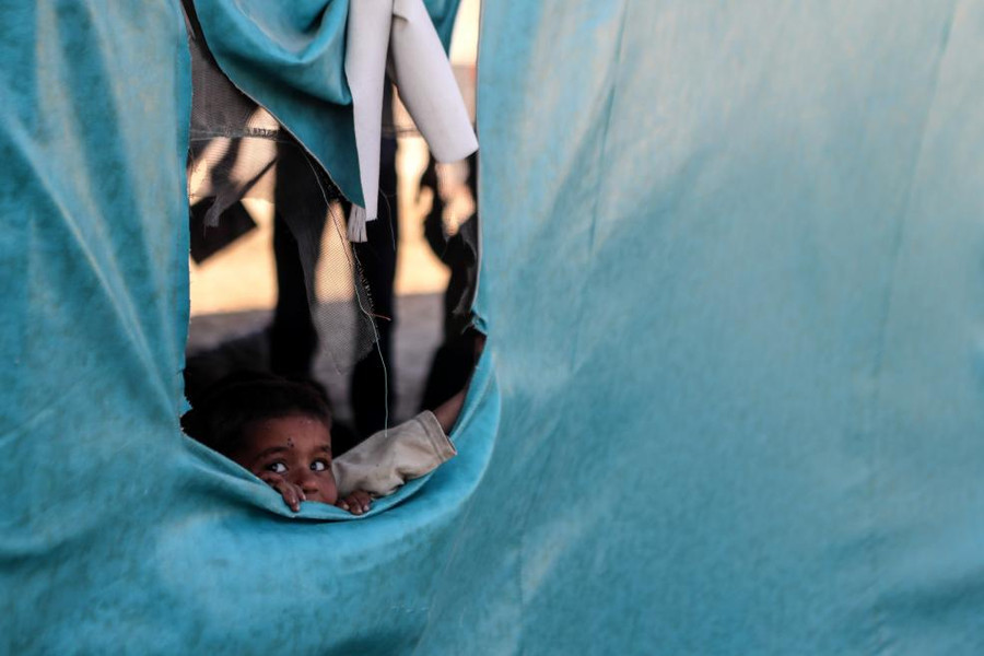 Cậu bé này đang nhòm qua một túp lều được dùng làm lớp học tại một trại dành cho các gia đình phải sơ tán trong thành phố đang bị quân phiến loạn nắm giữ ở al-Asha"ari, Syria.