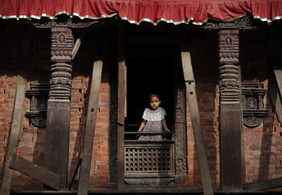 Một bé gái nhìn qua cửa sổ một ngôn đền ở Quảng trường Basantapur, Kathmandu, Nepal
