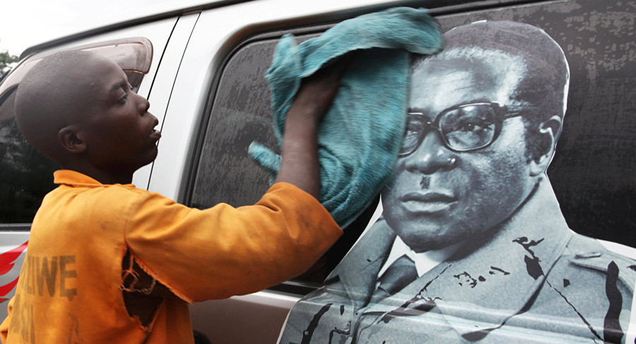 Một cậu bé đang lau bức ảnh Tổng thống Zimbabwe Robert Mugabe 