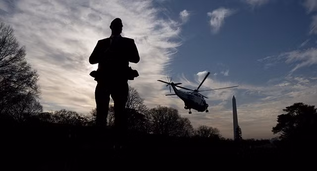 Một mật vụ Mỹ đứng canh gác khi chuyên cơ chở Tổng thống Trump rời Nhà trắng