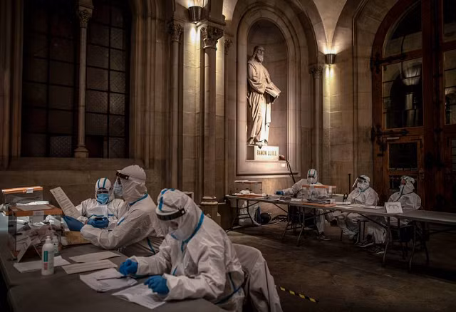 Nhân viên của điểm bỏ phiếu tại Đại học Barcelona, Tây Ban Nha mặc trang phục bảo hộ trong giờ bỏ phiếu cuối cùng. Việc này cho phép những người dương tính với COVID hoặc những người đang bị cách ly bỏ phiếu trong các cuộc bầu cử khu vực ở Catalan.