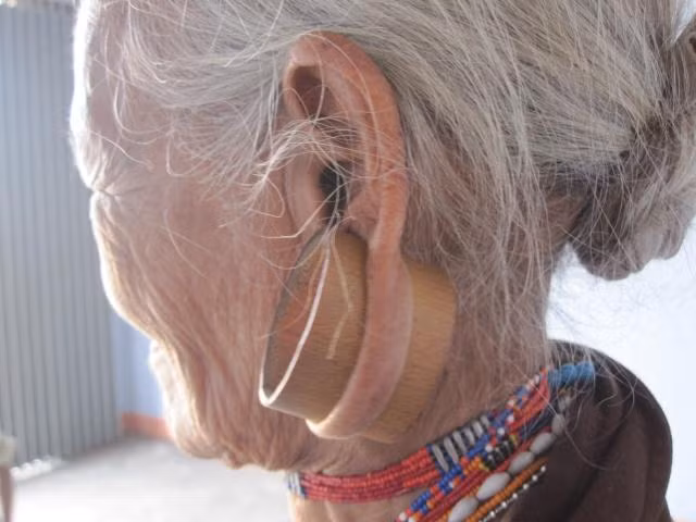 Lỗ tai trước đây đeo ngà voi, ngày nay thay bằng ống nứa.