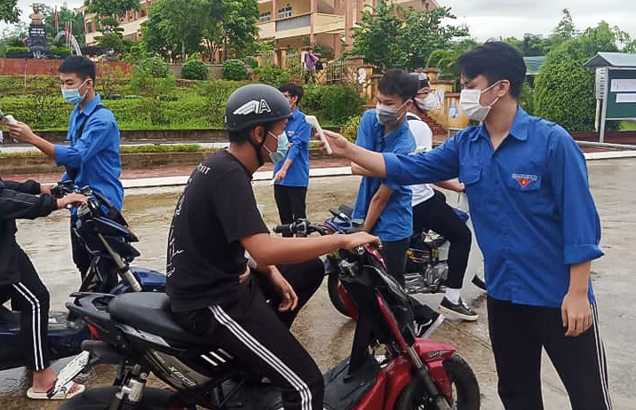 Thí sinh đến dự thi tuyển sinh lớp 10 được đo thân nhiệt và yêu cầu đeo khẩu trang, sát khuẩn.