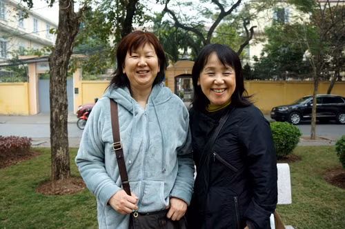 Hai người phụ nữ tỏ ra ngạc nhiên và òa lên thích thú khi nhìn thấy những người bán hoa đào trên phố.