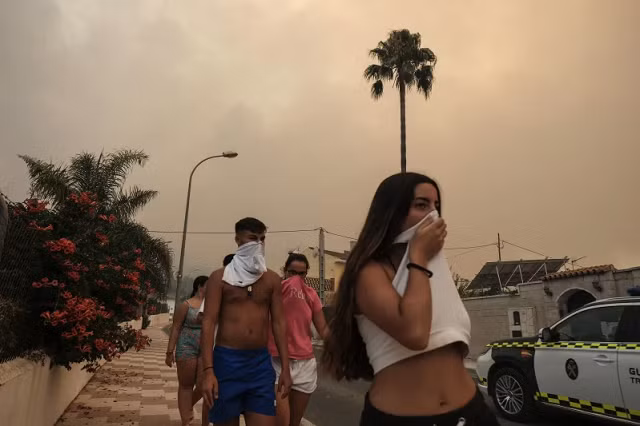 Người dân bịt mũi vì khói khi đám cháy rừng bùng phát gần khu dân cư ở Alhaurin de la Torre, Malaga, Tây Ban Nha