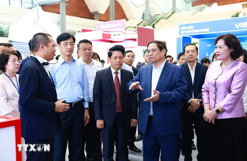 Thủ tướng Phạm Minh Chính tham quan trưng bày về ứng dụng chuyển đổi số trong lĩnh vực ngân hàng. (Ảnh: Dương Giang/TTXVN)
