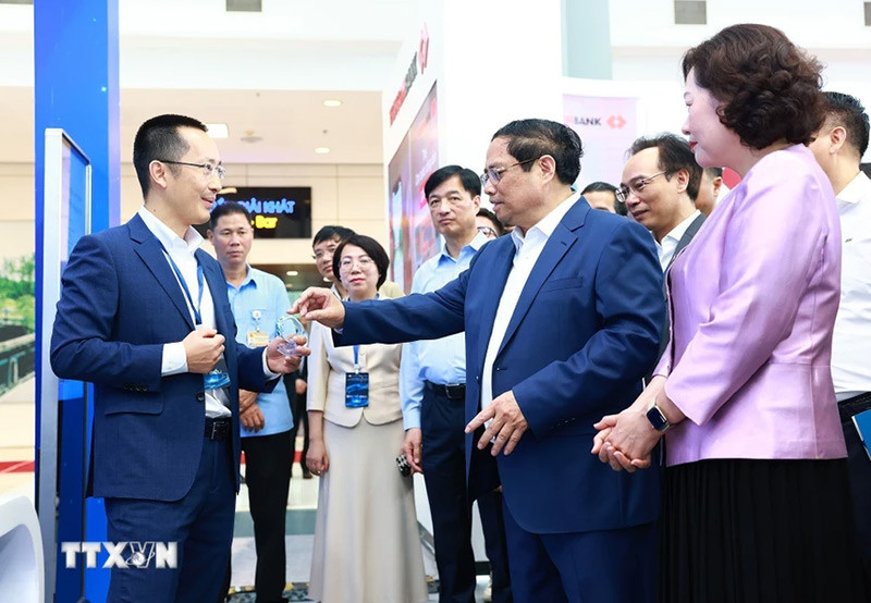 Thủ tướng Phạm Minh Chính tham quan trưng bày về ứng dụng chuyển đổi số trong lĩnh vực ngân hàng. (Ảnh: Dương Giang/TTXVN)