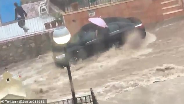 Một người cố gắng vào trong xe giữa dòng nước chảy mạnh. Một người cố gắng vào trong xe giữa dòng nước chảy mạnh.