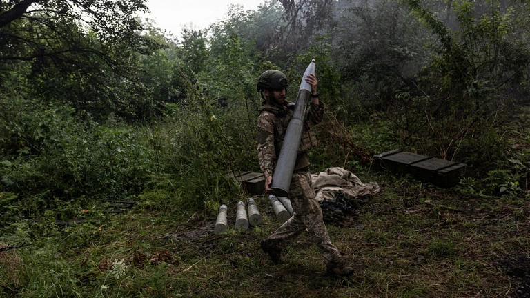 Một binh sĩ Ukraine mang theo một quả đạn pháo. (Ảnh: Getty Images)