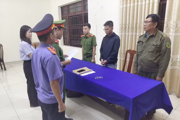 Công an tống đạt các Quyết định khởi tố vụ án, khởi tố bị can và Lệnh bắt tạm giam đối với Võ Nguyễn Duy An (áo đen). Ảnh: Công an cung cấp