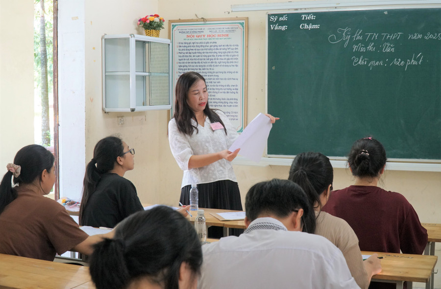 Giám thị hướng dẫn thí sinh điền đúng thông tin vào giấy làm bài thi môn Ngữ văn. Ảnh: Hồ Lài