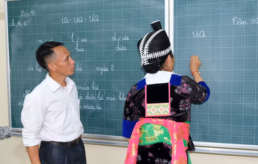 Thầy giáo Lỳ Bá Của (giáo viên Trường Phổ thông DTBT Tiểu học Hữu Khuông, Nghệ An) dạy học xóa mù chữ cho người dân. Ảnh: Hồ Lài