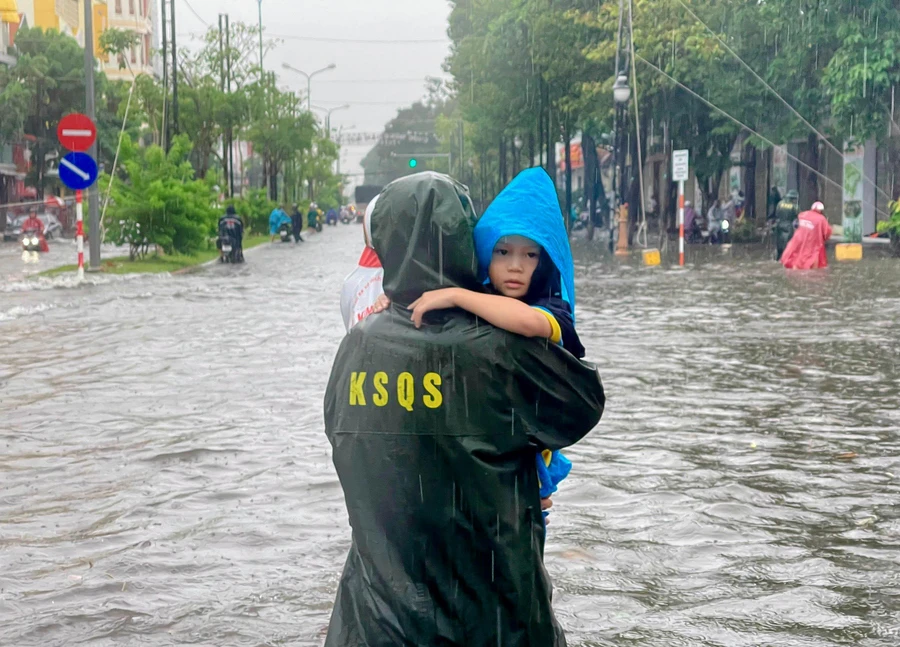 Cán bộ, chiến sĩ hỗ trợ người dân đưa trẻ nhỏ ra khỏi khu vực ngập sâu.