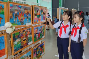Hai em học sinh đang ngắm các bức vẽ của các thí sinh tham gia hội thi vẽ tranh "Em vẽ sắc màu quê hương". Ảnh: Nhà thiếu nhi Bình Dương