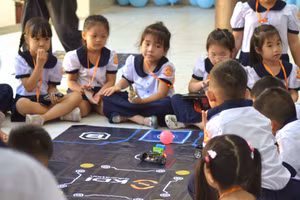 Các em học sinh thích thú với hoạt động điều khiển robot. Ảnh: H.P.