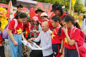 Nhiếp ảnh gia Nguyễn Á trò chuyện cùng các em học sinh tham quan triển lãm. Ảnh: L.N.